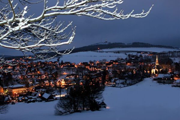 Blick vom winterlichen Schwartenberg auf das beleuchtete Spielzeugdorf Seiffen zur Weihnachtszeit